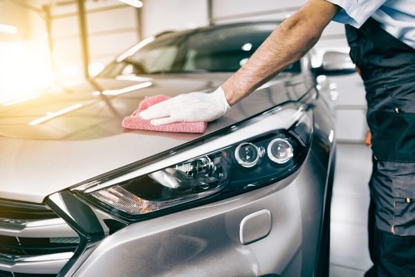 Car detailing - the man holds the microfiber in hand and polishes the car. Selective focus.