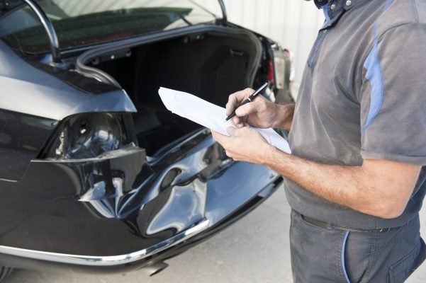 Service engineer inspecting a black car after a crash.